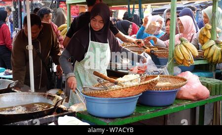 Jakarta, Indonesien - August 2019: Eine muslimische Frau sind braten Bananen zu verkaufen, während die Käufer warten. Stockfoto