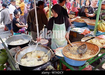 Jakarta, Indonesien - August 2019: Eine muslimische Frau sind braten Bananen zu verkaufen, während die Käufer warten. Stockfoto