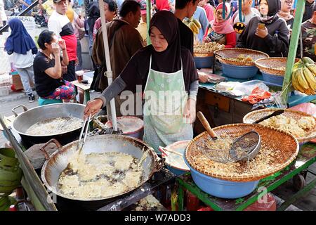 Jakarta, Indonesien - August 2019: Eine muslimische Frau sind braten Bananen zu verkaufen, während die Käufer warten. Stockfoto