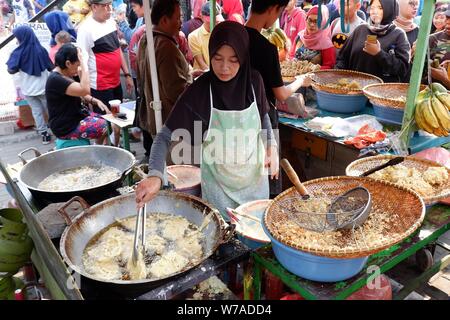 Jakarta, Indonesien - August 2019: Eine muslimische Frau sind braten Bananen zu verkaufen, während die Käufer warten. Stockfoto