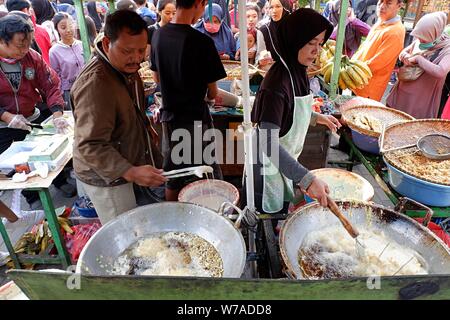 Jakarta, Indonesien - August 2019: ein Mann & Frau Paar braten Snacks zum Verkauf im eigenen Street Food stand. Stockfoto