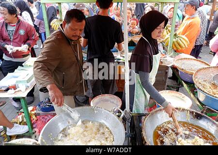 Jakarta, Indonesien - August 2019: ein Mann & Frau Paar braten Snacks zum Verkauf im eigenen Street Food stand. Stockfoto