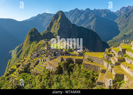 Ein paar Touristen genießen den Blick von der landwirtschaftlichen Terrassen über die verlorenen Inka Machu Picchu bei Sonnenuntergang, Cusco, Peru ruinieren. Stockfoto