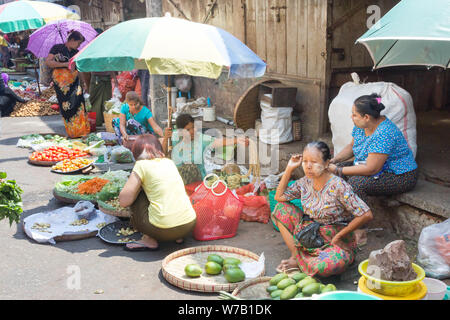 Yangon, Myanmar-Mai 4. 2014: Frauen warten auf Kunden in einem Straßenmarkt. Es gibt viele solcher Märkte in der Stadt. Stockfoto