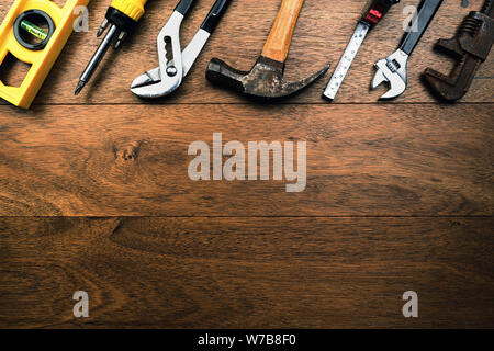 Grunge rusty Handwerker Werkzeuge wie Wasser, Zangen, Schraubendreher, Hammer und Maßband auf Holzbohlen mit Raum für Schreiben Stockfoto