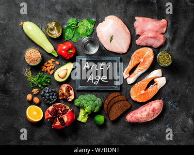 Anti Age Menü Konzept. Verschiedene Lebensmittelzutaten und Schiefertafel mit Anti Age Worte auf dunklem Hintergrund. Top View oder flach. Stockfoto