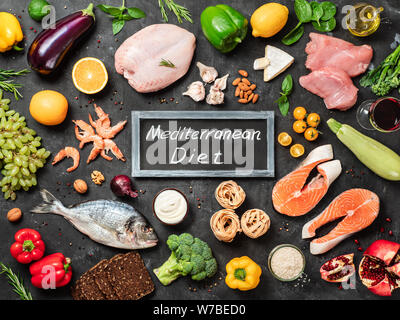 Mediterrane Ernährung Konzept. Ansicht von oben von Lebensmittelzutaten und Schiefertafel mit Worten mediterrane Ernährung in der Mitte. Der dunkle Hintergrund. Flach. Stockfoto