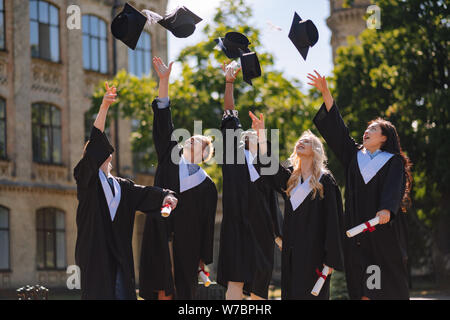 Absolventen suchen an ihre Herren Caps in der Luft. Stockfoto