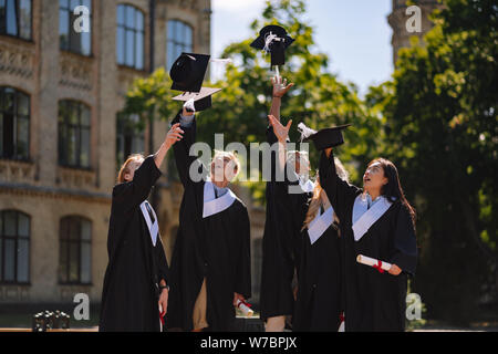 Absolventen, die versuchen, ihre Meister Kappen zu fangen. Stockfoto