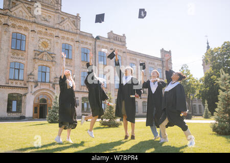 Studenten springen ihre Kappen Fang nach Staffelung. Stockfoto