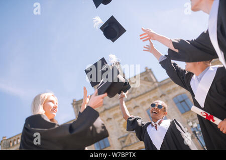 Fröhliche Schulabgänger fangen ihre Herren caps. Stockfoto