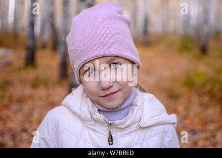 Portrait eines Mädchens mit blauen Augen, die in den Wald steht. Jugendlicher Mädchen in einen Hut und Mantel vor dem Hintergrund einer goldgelben Herbst Wald. cop Stockfoto