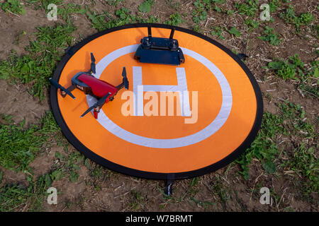 Russland, Tatarstan, 15. Juni 2019. Brummen auf der heliport.Drone Telefon- und Control Panel auf eine orange Hubschrauberlandeplatz auf dem Gras. Stockfoto