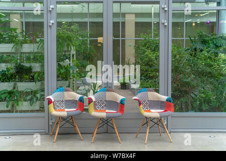 Russland, Tatarstan, 13. April 2019. Drei mehrfarbige Stühle auf dem Hintergrund der Grünflächen im Innenbereich. Interior Design. Schule. Stockfoto