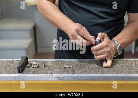 Die Pistole mit 9 19 Patronen. Die Hände der Männer kostenlos die Pistole mit Munition. close-up Stockfoto