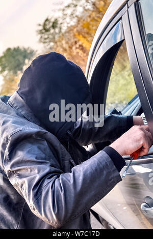 Dieb tragen schwarze Kleidung stehlen ein Auto Stockfoto