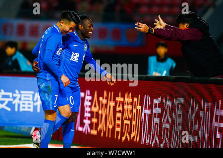 Kamerunischer Fußballspieler Christian Bassogog Henan Jianye, Mitte, feiert mit seinen Mannschaftskameraden Hu Jinghang und ihr Trainer Guo Guangqi nach sco Stockfoto