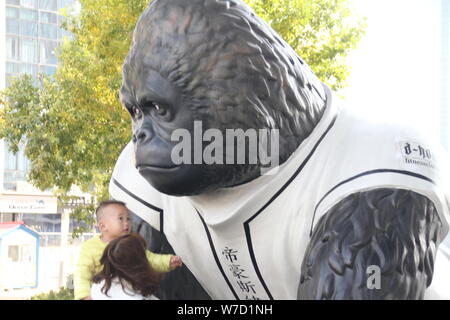 Ein Kind prüft ein Gorilla Skulptur auf der Straße in Ji'Nan, der ostchinesischen Provinz Shandong, 23. Oktober 2017. Ein Gorilla Skulptur dargestellt Stockfoto
