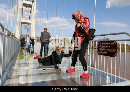 Touristen posieren für Fotos, die auf der 3D Glas - untere Brücke über den Gelben Fluss in Zhongwei Stadt im Nordwesten Chinas autonomen Region Ningxia Hui, 21 O Stockfoto