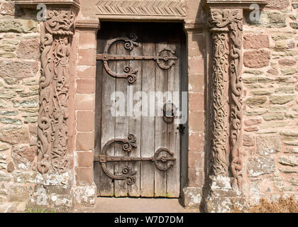 Tür und Bogen mit kunstvollen Schnitzereien über Süden Tür. Einschließlich der Engel in der Mitte. Kirche St. Maria und St. David, Kilpeck, Herefordshire Stockfoto