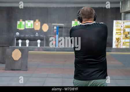 Mann im Schießstand in Action mit GLOCK 19, Ansicht von hinter o Holding eine Pistole Ziel weg von der Kamera, die mit der geringen Tiefe von Fiel Stockfoto