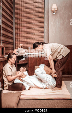 Frau erhalten Ihr Thai Massage von zwei Masseurinnen. Stockfoto