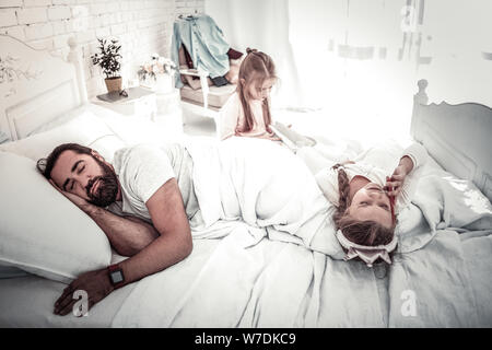 Vater schlafen, während seine Kinder spielen auf dem Bett Stockfoto