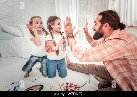 Gerne Vater hoch fünf seiner Kinder, die malen Stockfoto