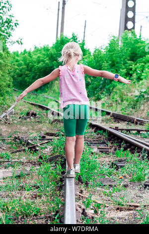 Das kleine Mädchen geht auf den alten, verlassenen Eisenbahnen Stockfoto