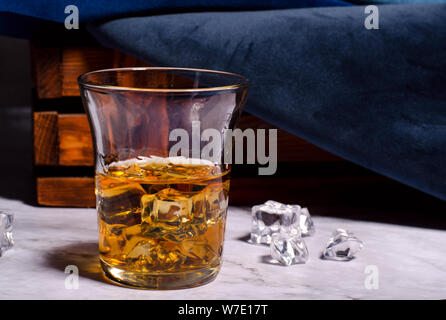 Whiskey oder Cognac in das Glas mit dem Eiswürfel. Alkohol trinken gegen den dunklen Hintergrund. Stockfoto