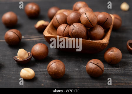 Nahaufnahme von Macadamia-nüssen auf schwarzen Holztisch Stockfoto