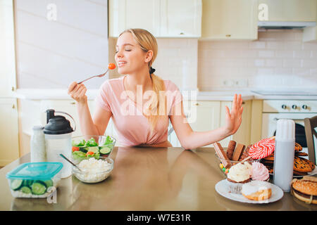 Netten Jungen gut gebauten Modell eting gesundes Essen in der Küche am Tisch. Sie sagt, keine Mahlzeit zu Spam. Allein in der Küche. Tageslicht. Gesunder Lebensstil Stockfoto