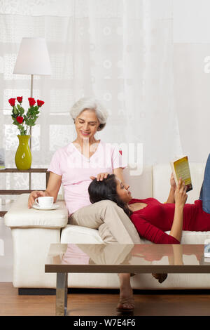 Alte Frau mit einer Tasse Tee mit ihrer Enkelin Buch Stockfoto