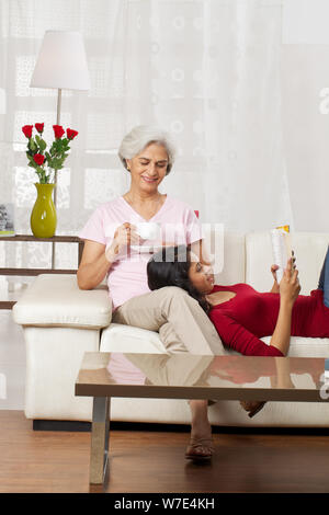 Alte Frau mit einer Tasse Tee mit ihrer Enkelin Buch Stockfoto