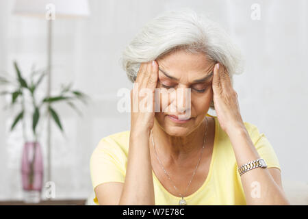 Alte Frau leidet unter Kopfschmerzen. Stockfoto