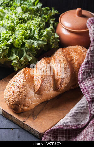 Frisches Brot mit Sesam bestreut Samen auf einen hölzernen Tisch. Stockfoto