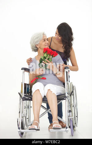 Junge Frau, die ihrer Großmutter Blumenstrauß gibt Stockfoto