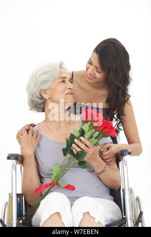 Junge Frau, die ihrer Großmutter Blumenstrauß gibt Stockfoto