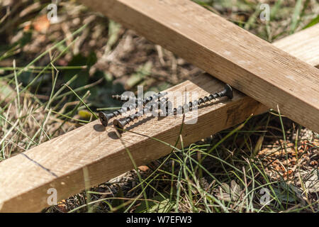 Mehrere selbstschneidende Schrauben auf Holzplatten. Bau, Montage von Holzzaun Stockfoto