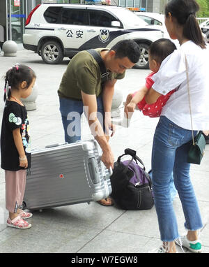 ---- Ein chinesisches Mädchen und ihre Mutter, die die jüngere Schwester Blick an den Vater hält, wie sie am Bahnhof in Yichang Yichang City warten, cen Stockfoto