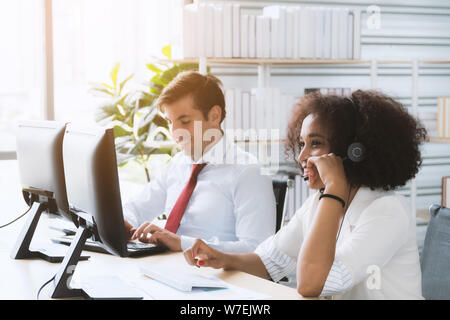Afrikanische amerikanische Frau Call Center Mitarbeiter durch ihr Team begleitet. Lächelnd customer support Operator bei der Arbeit. Lächelnd customer support Operator in wor Stockfoto