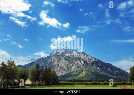 Sommer Landschaft auf Sportplätzen mit grünem Rasen und Alpen durch blauen Himmel in Österreich Stockfoto