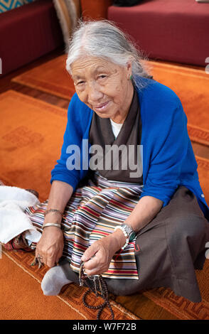 Stellen Portrait eines älteren Nepalesischen Sherpa Buddhistischen an einem Tempel in Elmhurst, Queens, New York sitzt. Stockfoto