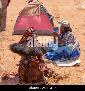 Herero, Himba Frauen an einem Begräbnis sammeln, Zelte und Hütten können im Hintergrund gesehen werden. Kaokoveld, Namibia Stockfoto