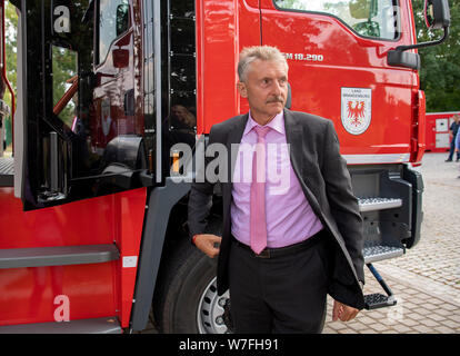 Zossen, Deutschland. 06 Aug, 2019. Karl-Heinz Schröter (SPD), Minister des Innern des Landes Brandenburg, steht bei einem Brand des Motors während der feierlichen Einweihung des neuen Standorts der Staatlichen Feuerwehr Schule in Wünsdorf. Mit dem neuen Standort der staatlichen Schule und technische Einrichtung für Brand- und Katastrophenschutz des Landes Brandenburg, die erhöhte Nachfrage nach Aus- und Weiterbildung der Feuerwehren, kurzfristig gewährleistet werden. Credit: Monika Skolimowska/dpa-Zentralbild/dpa/Alamy leben Nachrichten Stockfoto