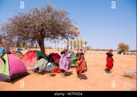 Herero Frauen an einem Begräbnis sammeln, Zelte und Hütten können im Hintergrund gesehen werden. Kaokoveld, Namibia Stockfoto