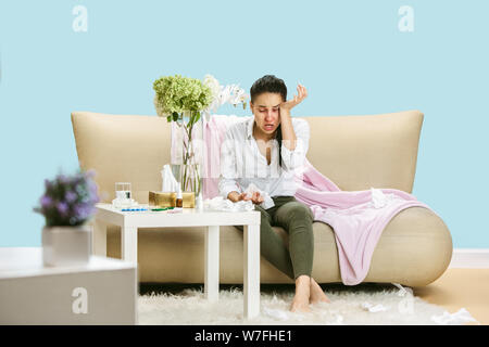 Junge Frau mit hausehold Staub oder saisonale Allergien. Niesen in der Serviette und sitzt von gebrauchten Servietten auf dem Boden und einem umgeben. Arzneimittel ohne Ergebnis. Healthcare Konzept. Stockfoto