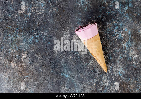 Nahaufnahme von Eis in der Wafer Kegel, mit Schokolade Topping auf einem dunklen konkreten Hintergrund, Ansicht von oben Stockfoto