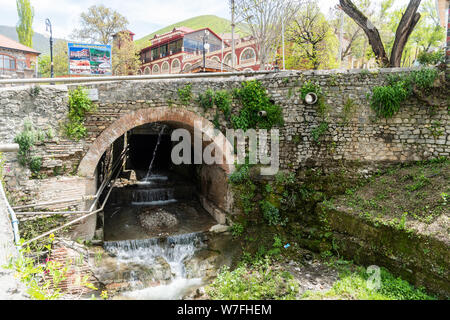 Sheki, Aserbaidschan - 29. April 2019. Historische Steinbrücke aus dem 18. Jahrhundert, in Scheki, Aserbaidschan, mit der auf die umliegenden Gebäude. Stockfoto