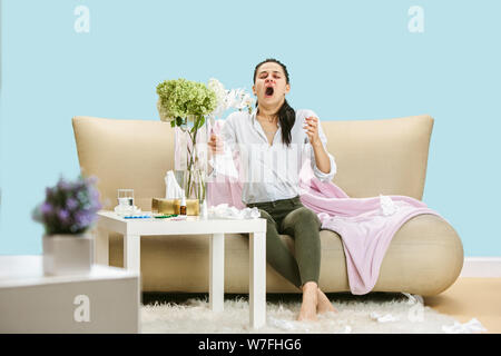 Junge Frau mit hausehold Staub oder saisonale Allergien. Niesen in der Serviette und sitzt von gebrauchten Servietten auf dem Boden und einem umgeben. Arzneimittel ohne Ergebnis. Healthcare Konzept. Stockfoto